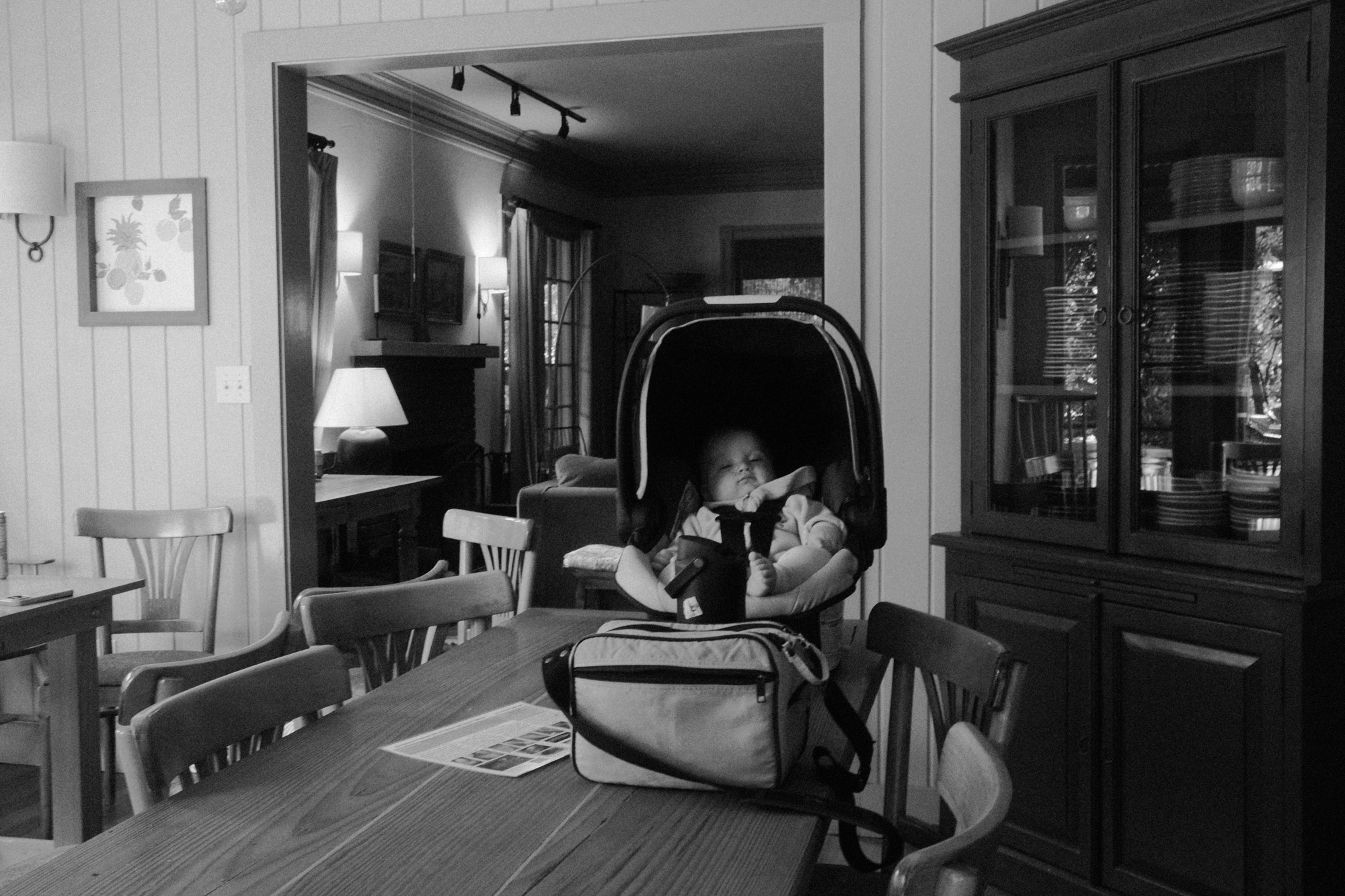 Black-and-white documentary photograph of a quiet domestic interior with a seated figure.
