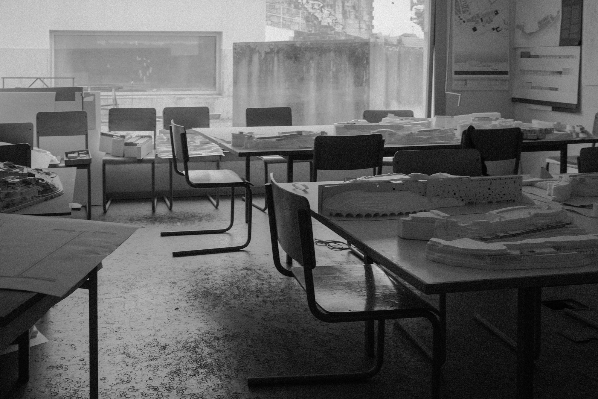 Black-and-white documentary photograph of an empty classroom in an education program.