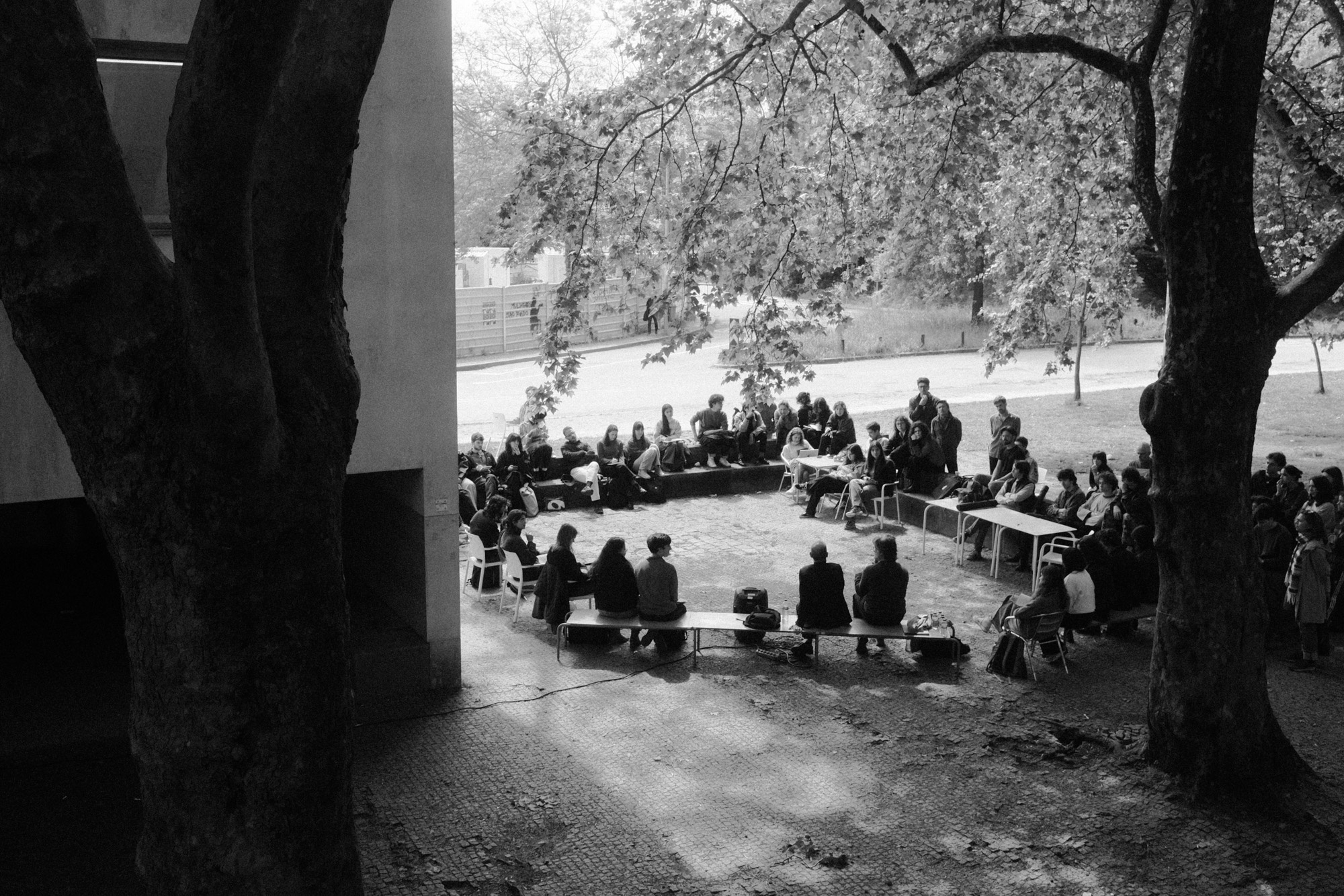Black-and-white documentary photograph of people gathered under trees.