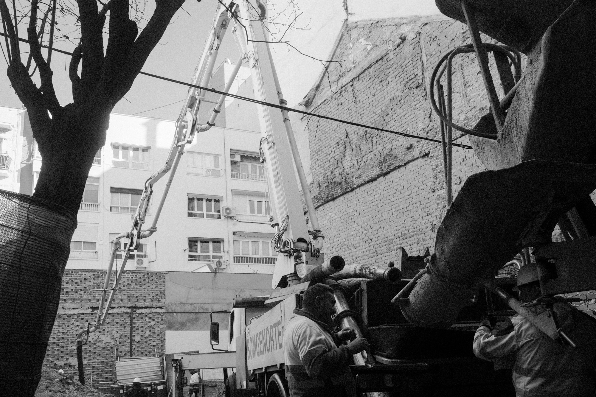 Black-and-white documentary photograph of people working at an urban site.